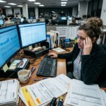 Stressed employee surrounded by stacks of invoices illustrating high accounts payable error rates in a busy office.